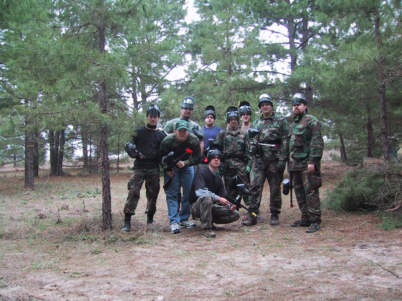 Paintball players posing together among the trees