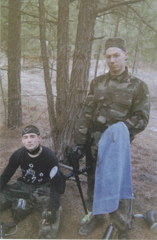 Two people posing beside a pine tree
