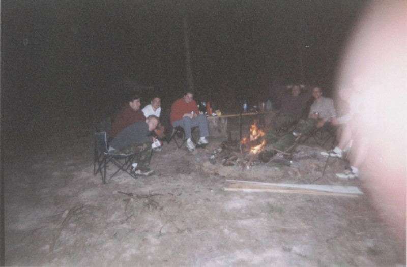 Campers seated around a fire after dark