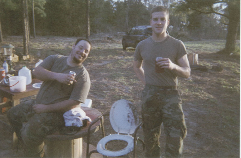 Two people beside a cooler and camp supplies