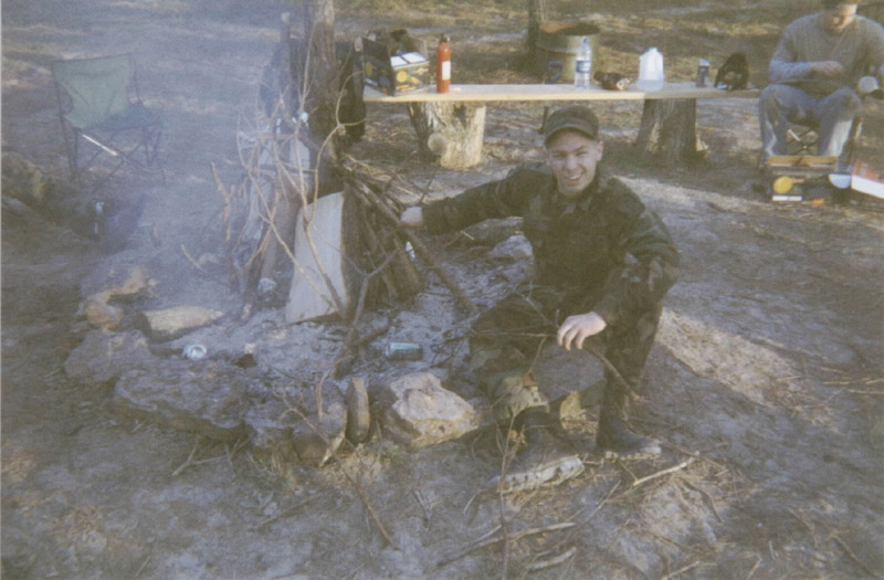 Person beside a smoky campfire