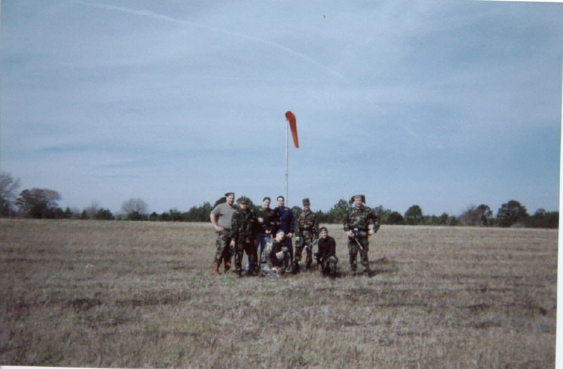 Group of players posing in an open field beneath a windsock