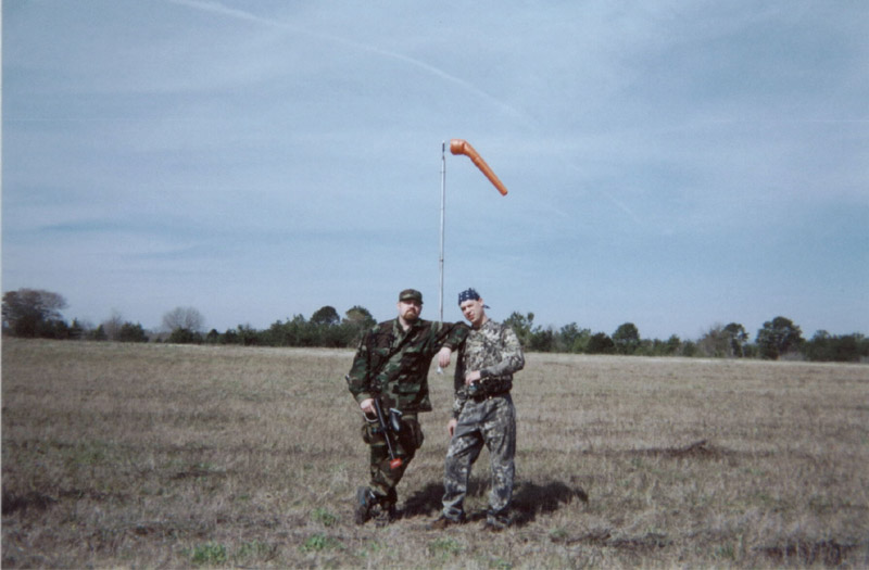 Two players standing in a grassy field beneath a windsock
