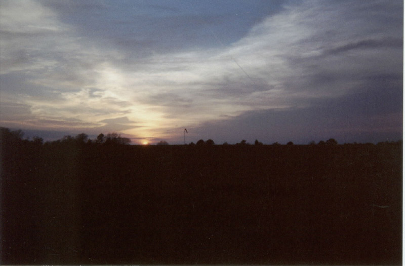 Sun setting below a cloud-filled sky