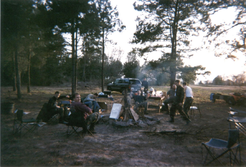 Campers and supplies gathered near a smoky fire