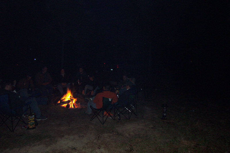 Campers seated around a fire in the dark