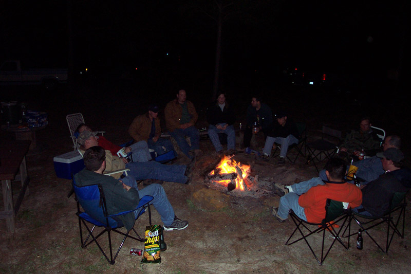 People gathered in folding chairs around a campfire