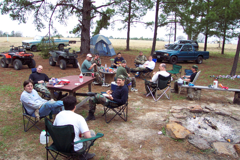 Campers seated around a picnic table under pine trees