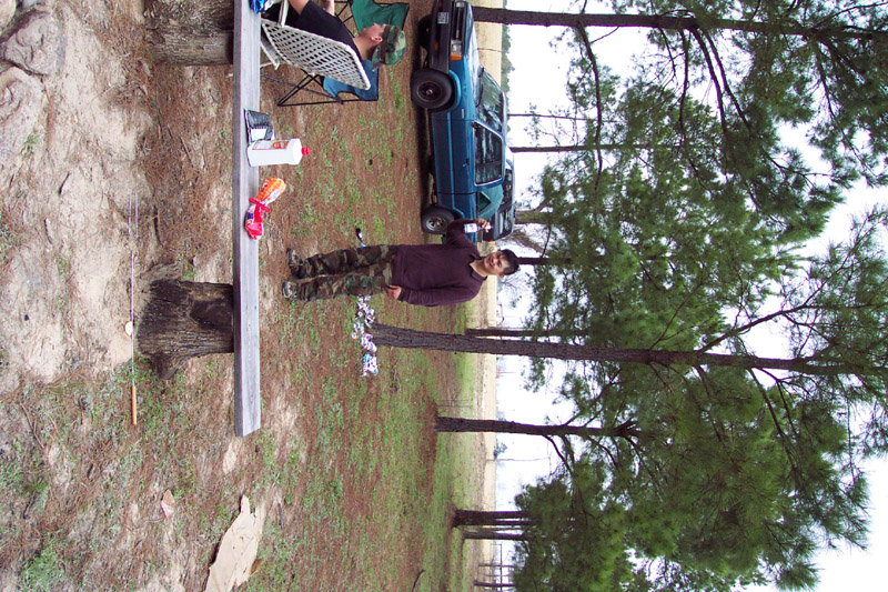 Person standing among tents and campsite supplies