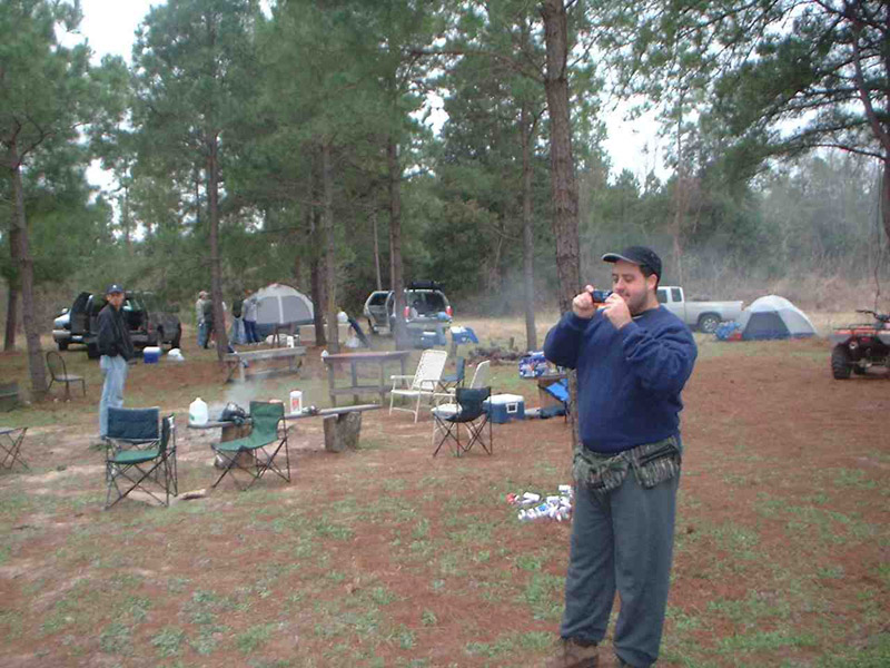 Person holding a cup at a wooded campsite
