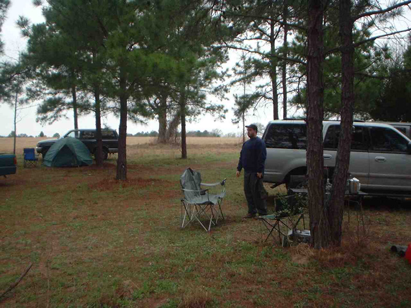 Camper standing near a pickup truck and folding chairs