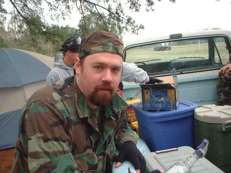 Camouflaged player seated beside coolers and a pickup truck