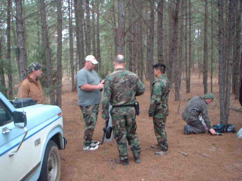 Players gathered beside a vehicle in the woods