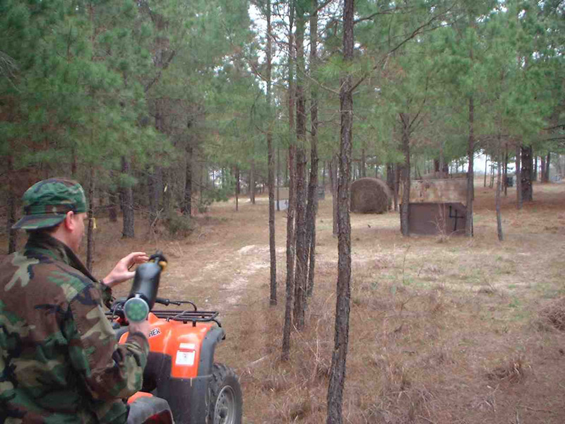 Player beside an all-terrain vehicle on a wooded field